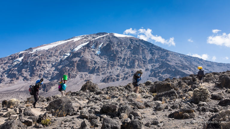 Mount Kilimanjaro with snow peak, volcanic cones, and rugged terrain under clear sky