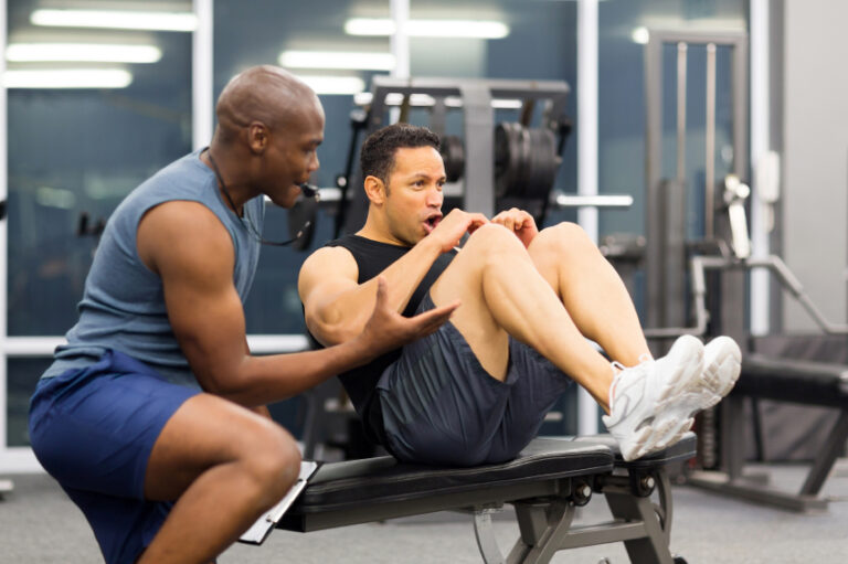 Middle-aged man working out with guidance from a personal trainer in a gym