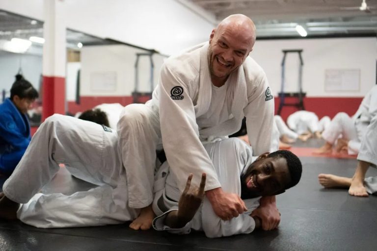 Two athletes practicing Brazilian Jiu-Jitsu grappling on mats inside a training gym